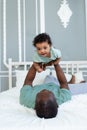 Happy smiling African american dad with baby son on bed at home cuddling and playing, happy family, father`s day Royalty Free Stock Photo