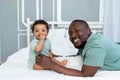 Happy smiling African american dad with baby son on bed at home cuddling and playing, happy family, father`s day Royalty Free Stock Photo