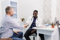 A happy smiling African-American male doctor talks to a patient while sitting at a table. Royalty Free Stock Photo