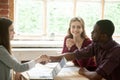 Young multiethnic couple shaking hands with real estate agent.