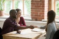 Young multiethnic couple shaking hands with real estate agent.