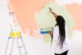 Happy smiling african american woman painting interior wall of new house. Redecoration, renovation, apartment repair and Royalty Free Stock Photo