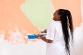 Happy smiling african american woman painting interior wall of new house. Redecoration, renovation, apartment repair and Royalty Free Stock Photo