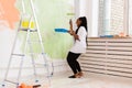 Happy smiling african american woman painting interior wall of new house. Redecoration, renovation, apartment repair and Royalty Free Stock Photo