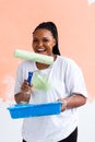 Happy smiling african american woman painting interior wall of new house. Redecoration, renovation, apartment repair and Royalty Free Stock Photo