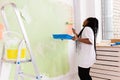 Happy smiling african american woman painting interior wall of new house. Redecoration, renovation, apartment repair and Royalty Free Stock Photo