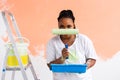 Happy smiling african american woman painting interior wall of new house. Redecoration, renovation, apartment repair and Royalty Free Stock Photo