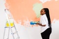 Happy smiling african american woman painting interior wall of new house. Redecoration, renovation, apartment repair and Royalty Free Stock Photo