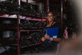 Happy smiling african american worker woman wear spectacles holding clipboard standing in factory auto parts. female employee