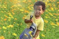 Happy smiling African boy with black curly hair watering yellow orange cosmos flower garden. Kid spending time outdoors in Royalty Free Stock Photo