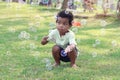 Happy smiling African boy blowing soap bubbles at green garden. Child having fun with bubble in summer park. Kid spending time Royalty Free Stock Photo