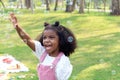 Happy smiling African girl with black curly hair blowing and playing with soap bubbles at green garden. Cute child has fun with Royalty Free Stock Photo