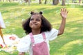 Happy smiling African girl with black curly hair blowing and playing with soap bubbles at green garden. Cute child has fun with Royalty Free Stock Photo