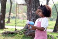 Happy smiling African girl with black curly hair making soap bubbles with blowing bubble gun toy at green garden. Kid spending Royalty Free Stock Photo