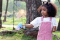 Happy smiling African girl with black curly hair making soap bubbles with blowing bubble gun toy at green garden. Kid spending Royalty Free Stock Photo