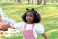 Happy smiling African girl with black curly hair playing with soap bubbles making from blowing bubble gun toy at green garden. Royalty Free Stock Photo