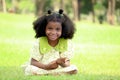 Happy smiling African girl with black curly hair sets on green grass meadow garden Royalty Free Stock Photo