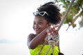 Happy smiling African girl with black curly hair wearing brightly colored swimsuit, sitting on swing at beach outdoor, beautiful Royalty Free Stock Photo