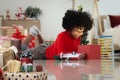 Happy smiling African girl with curly hair laying down on floor surround with Christmas present, cute kid opening gift box, Royalty Free Stock Photo