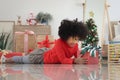 Happy smiling African girl with curly hair laying down on floor surround with Christmas present, cute kid opening gift box, Royalty Free Stock Photo