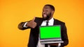 Happy smiling afro-american male showing prekeyed laptop and thumbs-up gesture