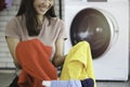 Happy smiling Asian beautiful young woman doing laundry at laundry room with washing machine, housewife doing housework and Royalty Free Stock Photo