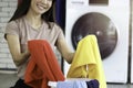 Happy smiling Asian beautiful young woman doing laundry at laundry room with washing machine, housewife doing housework and Royalty Free Stock Photo