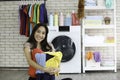 Happy smiling Asian beautiful young woman doing laundry at laundry room with washing machine, housewife doing housework and Royalty Free Stock Photo