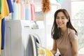 Happy smiling Asian beautiful young woman doing laundry at laundry room with washing machine, housewife doing housework and Royalty Free Stock Photo