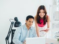 Happy smiling Asian business couple, young man and woman, colleagues using tablet and laptop computer. Royalty Free Stock Photo