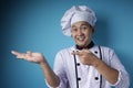 Happy Smiling Asian Chef Pointing Presenting Something on His Empty Hand Royalty Free Stock Photo
