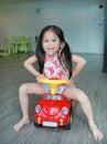 Happy smiling Asian child girl driving car toy at playroom Royalty Free Stock Photo