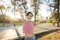 Happy smiling asian child girl in a mask under her chin,standing with arms outstretched in green nature,woman enjoy breathing Royalty Free Stock Photo