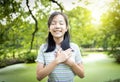 Happy smiling asian child girl standing in green nature,hold hands on heart,feel peace of mind,female teenage closed eyes,enjoy Royalty Free Stock Photo