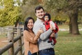 Happy smiling Asian Chinese mother and Caucasian father dad with baby girl in ladybug costume. Family in autumn fall park outdoors