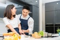 Happy Smiling Asian couple cooking in the kitchen at home. Young Man and beautiful woman having fun preparing vegetable for salad Royalty Free Stock Photo