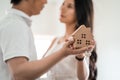 Happy smiling asian couple holding a model house, and danceing together with feeling happiness. Young loving couple with small