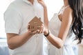 Happy smiling asian couple holding a model house, and danceing together with feeling happiness. Young loving couple with small