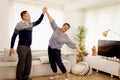 Happy smiling Asian elderly couple dancing in living room, romantic senior lover having fun together at home, mature retired Royalty Free Stock Photo