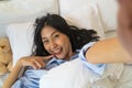 Happy smiling Asian girl using smartphone for selfie on the bed Royalty Free Stock Photo