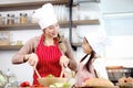 Happy smiling Asian mother and daughter wearing apron and chef hat, preparing fresh vegetables salad at kitchen, cute chef family Royalty Free Stock Photo