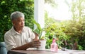 A happy and smiling Asian old elderly man is planting for a hobby after retirement in a home. Concept of a happy lifestyle and Royalty Free Stock Photo