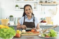 Happy smiling asian older woman in apron cut vegetables while cooking salad in kitchen. housewife cooking concept Royalty Free Stock Photo