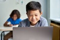 Happy Asian school boy using laptop computer at class in classroom. Royalty Free Stock Photo