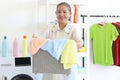 Happy smiling Asian senior elderly woman housewife carrying clothes basket for doing laundry at laundry room with washing machine Royalty Free Stock Photo