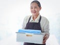 Happy smiling Asian senior elderly woman housewife carrying clothes basket for doing laundry at laundry room with washing machine Royalty Free Stock Photo