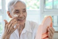Happy smiling asian senior woman apply sunscreen lotion on the cheek,protect her beautiful face,old elderly using skin care Royalty Free Stock Photo