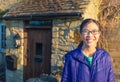 happy smiling asian teenager in front of old stone house of Cotwolds, England