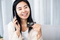 Happy and smiling Asian woman holding mobile phone calling the bank for credit card service Royalty Free Stock Photo