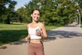 Happy smiling asian woman jogging in park. Healthy young female runner doing workout outdoors, running on streets Royalty Free Stock Photo